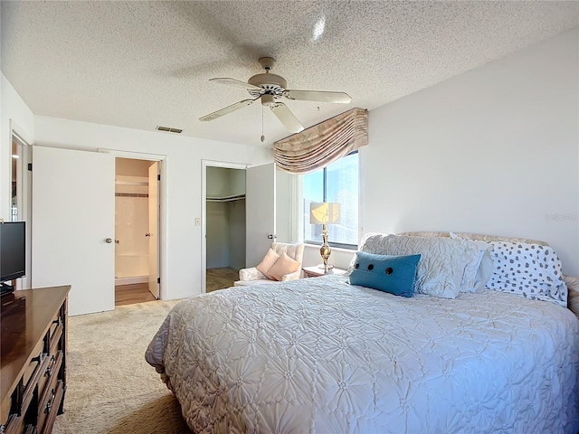 bedroom featuring carpet flooring, a walk in closet, a textured ceiling, ceiling fan, and a closet