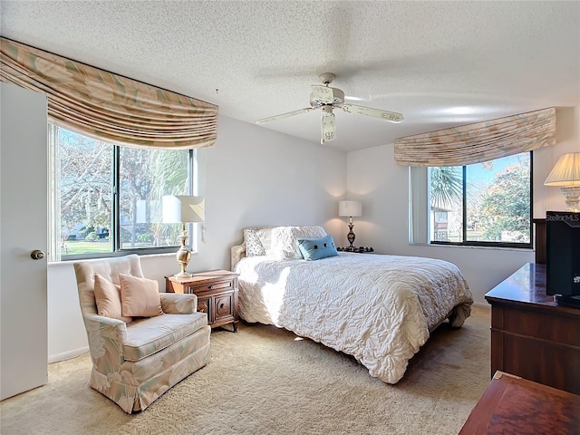 carpeted bedroom with ceiling fan and a textured ceiling