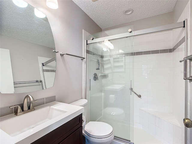 bathroom featuring a shower with door, vanity, a textured ceiling, and toilet