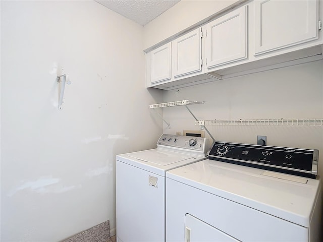 laundry room featuring washing machine and clothes dryer, cabinets, and a textured ceiling