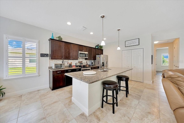 6407 SW 45th Ave, Ocala, FL 34474 - kitchen featuring appliances with stainless steel finishes, a kitchen breakfast bar, a center island with sink, dark brown cabinets, and backsplash