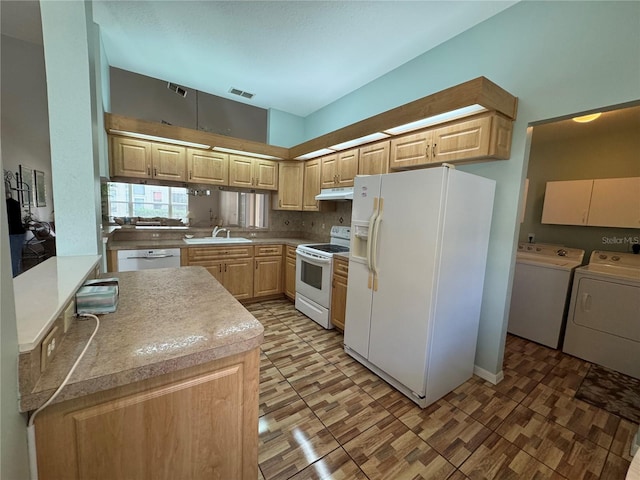 kitchen featuring white appliances, sink, light brown cabinetry, tasteful backsplash, and washing machine and clothes dryer