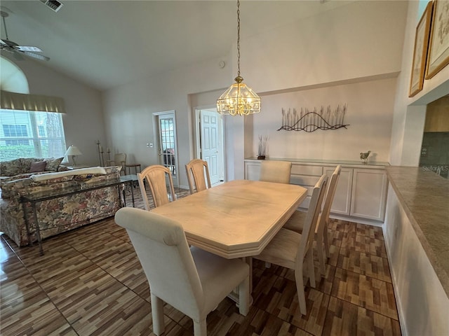 dining area featuring vaulted ceiling and ceiling fan with notable chandelier