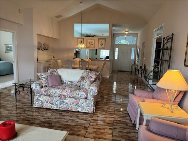 living room featuring high vaulted ceiling and a notable chandelier