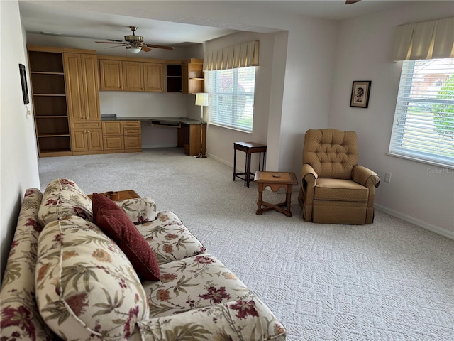 living room with ceiling fan, built in desk, and light carpet