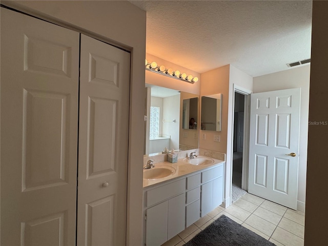 bathroom featuring tile patterned flooring, vanity, and a textured ceiling