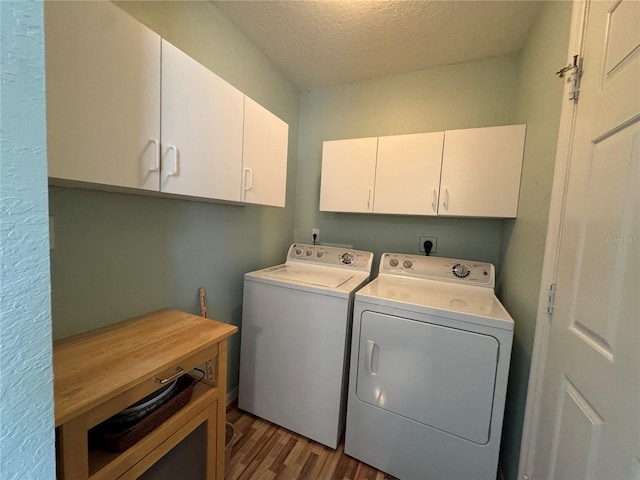 washroom featuring cabinets, a textured ceiling, dark wood-type flooring, and washing machine and clothes dryer