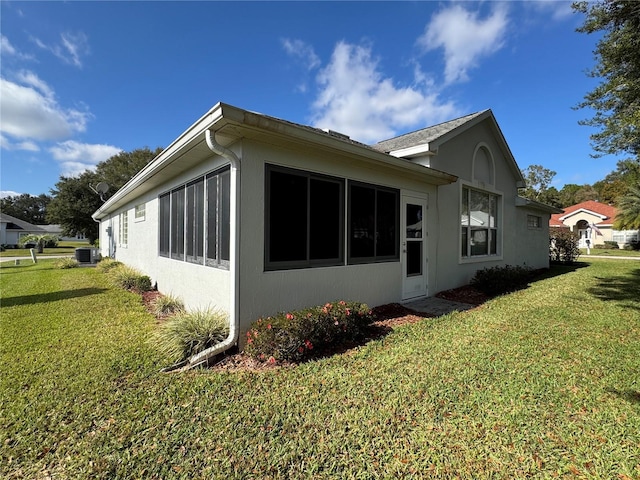 view of side of property with a lawn and central AC