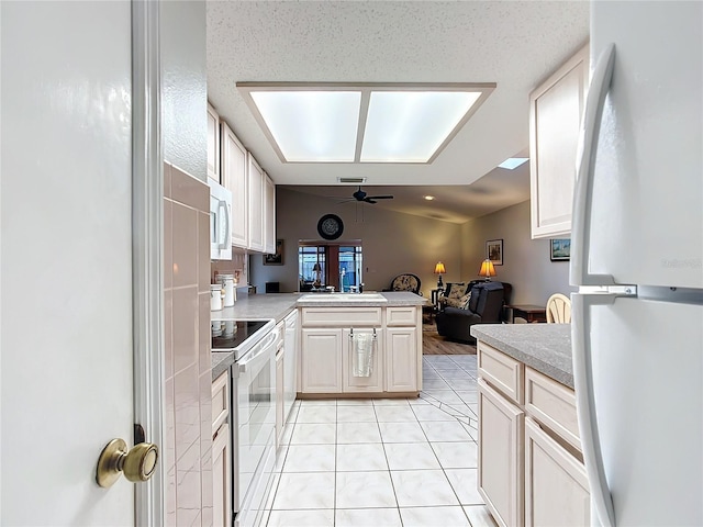 kitchen featuring white appliances, vaulted ceiling, ceiling fan, light tile patterned flooring, and kitchen peninsula