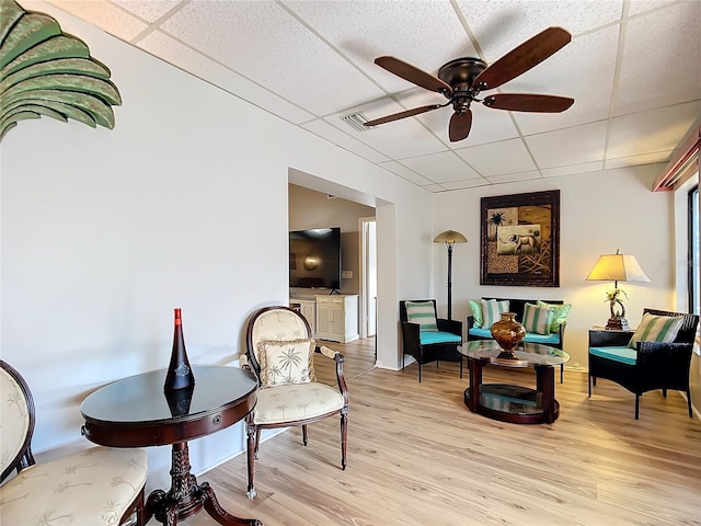 living area featuring a paneled ceiling, ceiling fan, and light hardwood / wood-style flooring