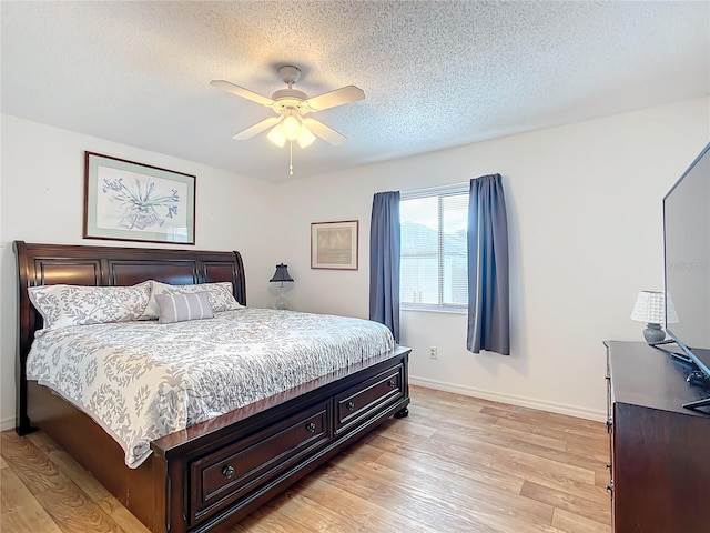 bedroom featuring ceiling fan, light hardwood / wood-style flooring, and a textured ceiling