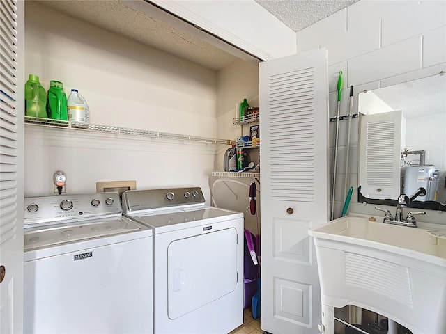 laundry room with a textured ceiling, gas water heater, washer and clothes dryer, and sink