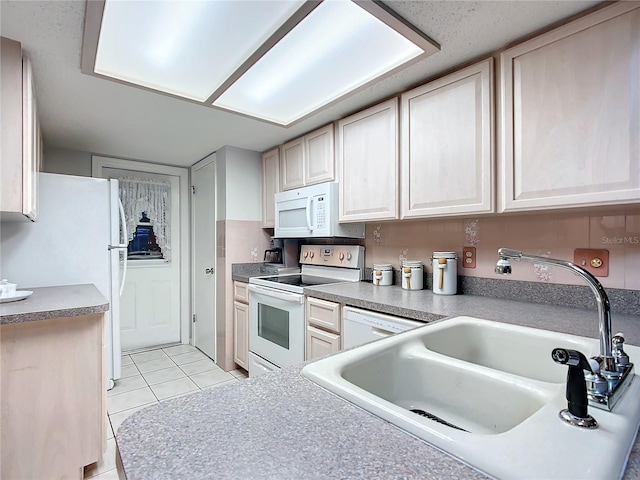 kitchen with light tile patterned floors, white appliances, and sink