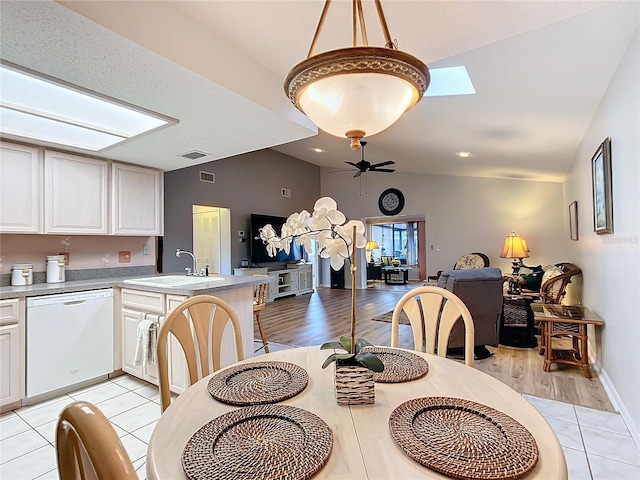 tiled dining area with lofted ceiling with skylight, ceiling fan, and sink