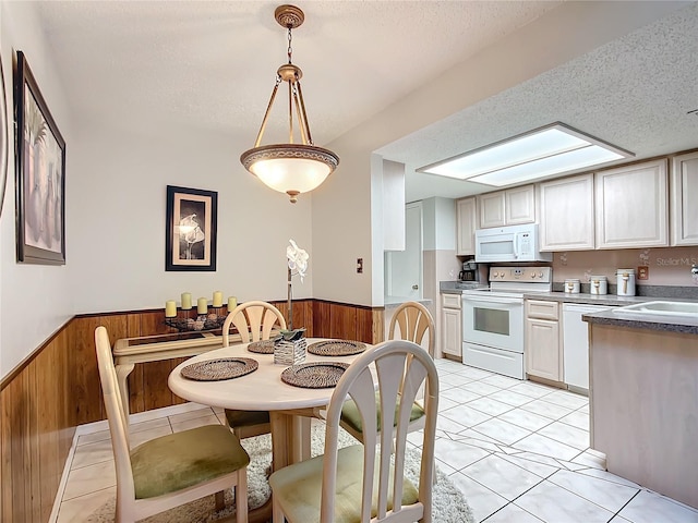 kitchen with a textured ceiling, wooden walls, pendant lighting, and white appliances