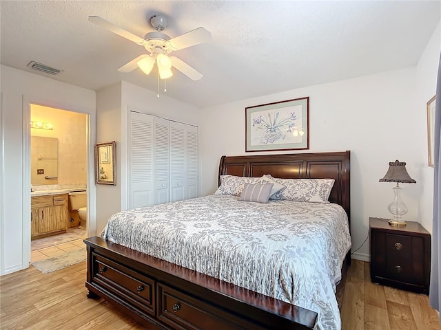 bedroom featuring connected bathroom, ceiling fan, a closet, and light wood-type flooring