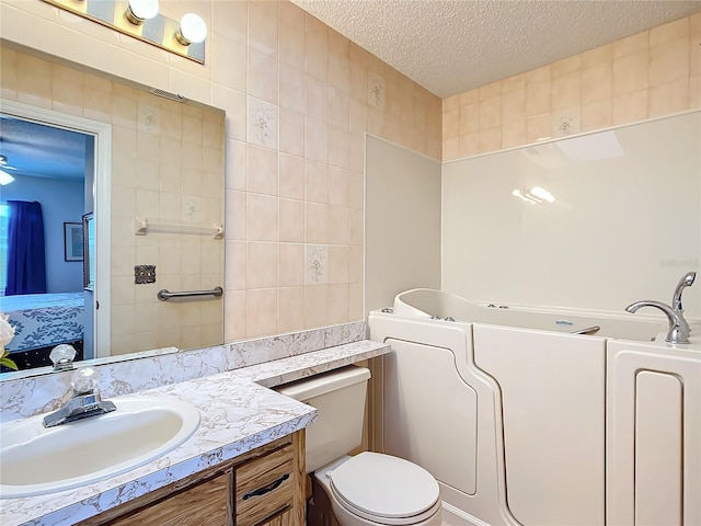 bathroom featuring vanity, a bathing tub, ceiling fan, toilet, and a textured ceiling