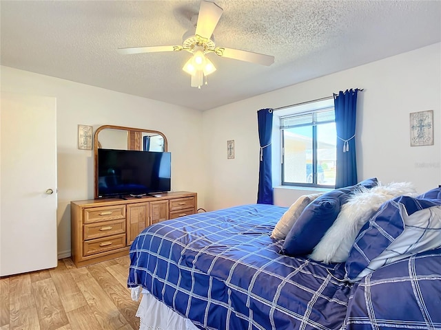 bedroom featuring ceiling fan, light hardwood / wood-style floors, and a textured ceiling