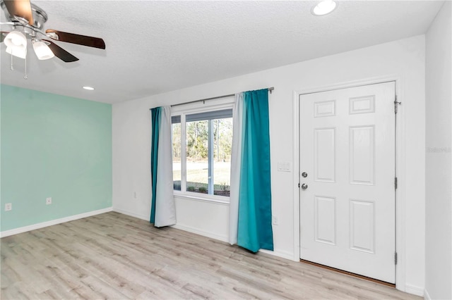 foyer entrance featuring a textured ceiling, light hardwood / wood-style flooring, and ceiling fan