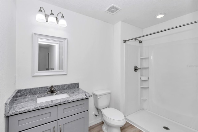 bathroom with hardwood / wood-style flooring, vanity, toilet, and walk in shower