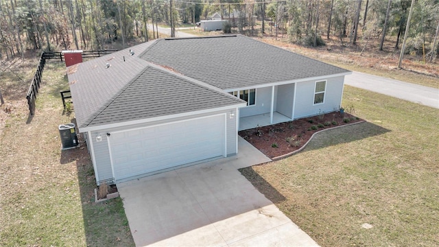 view of front of home with a front yard, a garage, and central air condition unit