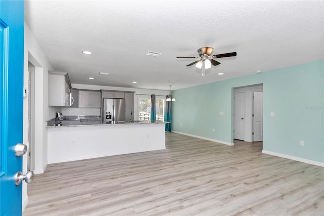 kitchen featuring gray cabinetry, kitchen peninsula, a textured ceiling, and appliances with stainless steel finishes