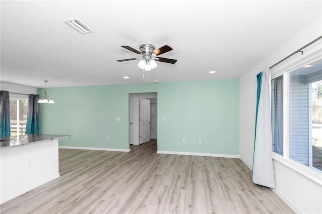 unfurnished living room with light hardwood / wood-style floors, a textured ceiling, and a wealth of natural light