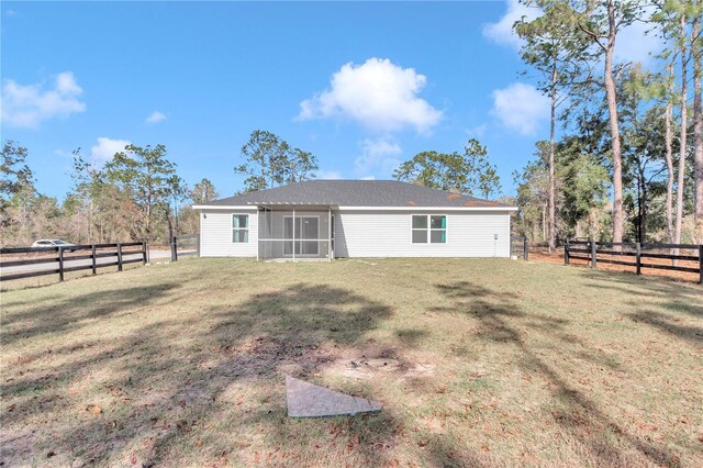 back of house featuring a sunroom and a lawn