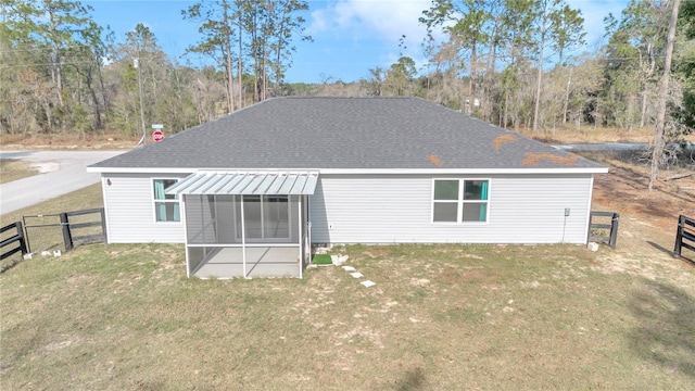 rear view of house with a lawn and a sunroom