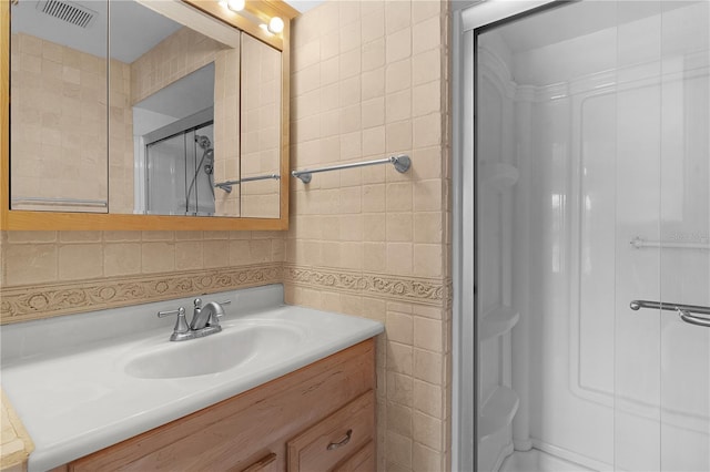 bathroom with backsplash, vanity, a shower with shower door, and tile walls