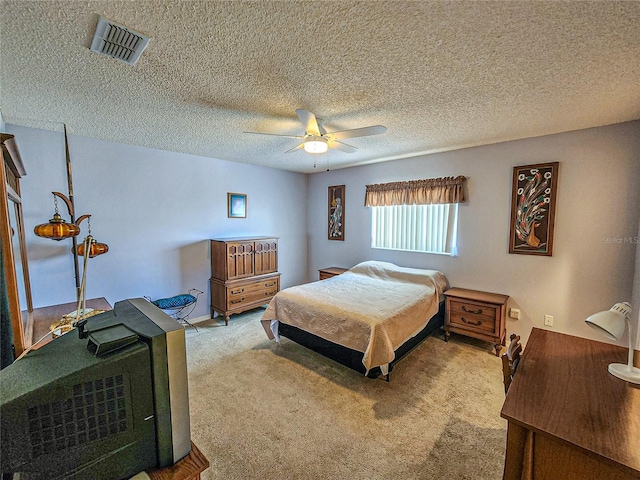 carpeted bedroom with ceiling fan and a textured ceiling