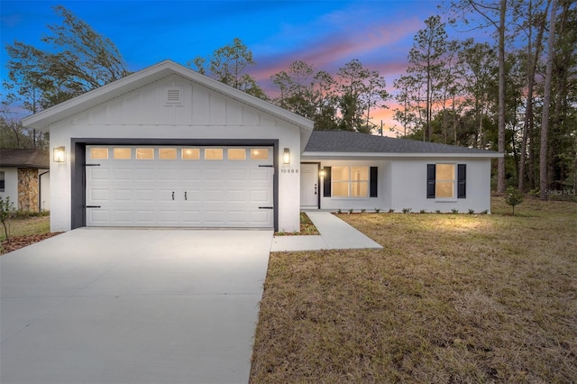 single story home featuring a garage and a yard