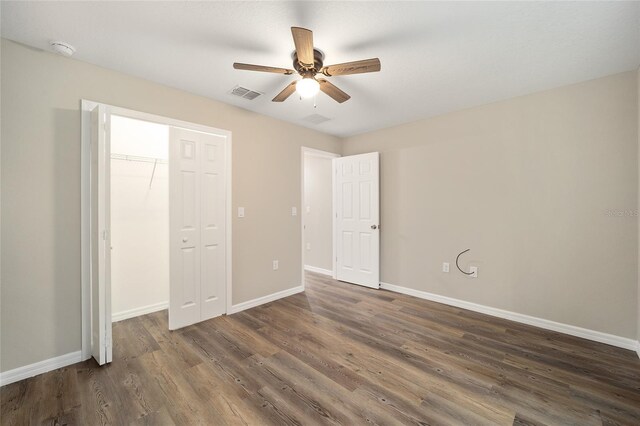 unfurnished bedroom with dark wood-type flooring, ceiling fan, and a closet