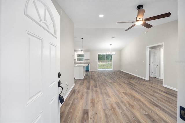 unfurnished living room featuring vaulted ceiling, ceiling fan with notable chandelier, and dark hardwood / wood-style flooring