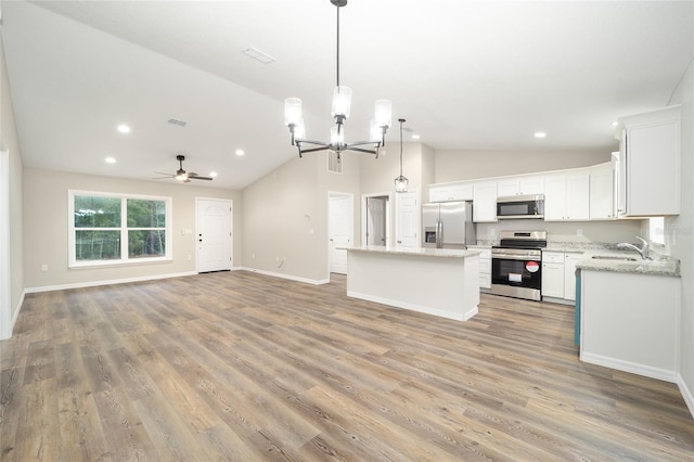 kitchen with sink, hanging light fixtures, stainless steel appliances, white cabinets, and a kitchen island