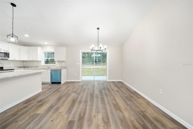 kitchen with hanging light fixtures, hardwood / wood-style flooring, white cabinets, and appliances with stainless steel finishes