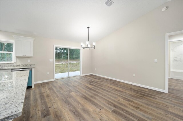 unfurnished dining area featuring lofted ceiling, dark wood-type flooring, and a notable chandelier