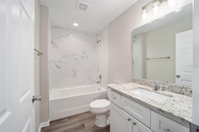 full bathroom with hardwood / wood-style flooring, tiled shower / bath, vanity, and toilet