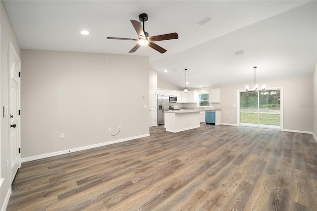 unfurnished living room with ceiling fan with notable chandelier, dark hardwood / wood-style floors, and vaulted ceiling