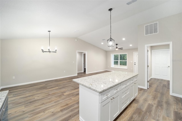 kitchen with vaulted ceiling, a kitchen island, hardwood / wood-style floors, decorative light fixtures, and white cabinetry