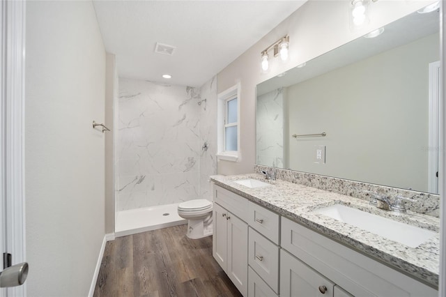 bathroom with vanity, hardwood / wood-style flooring, toilet, and tiled shower