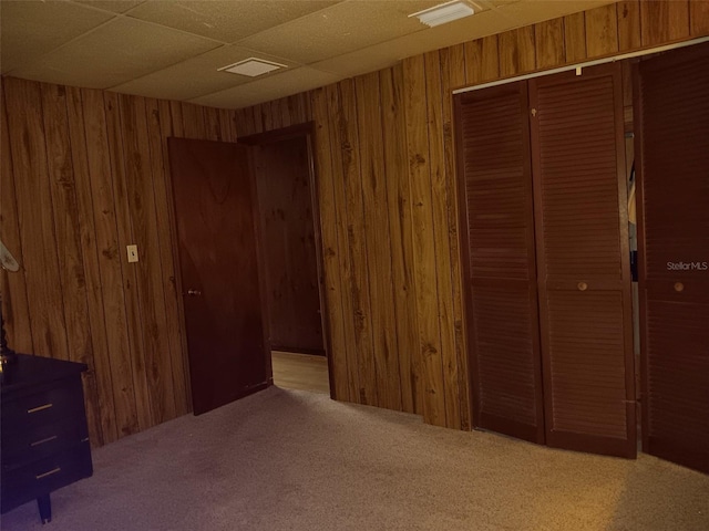 unfurnished bedroom featuring light carpet, wood walls, and a closet