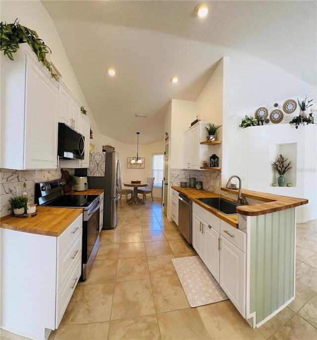 kitchen featuring stainless steel appliances, vaulted ceiling, sink, white cabinets, and butcher block counters