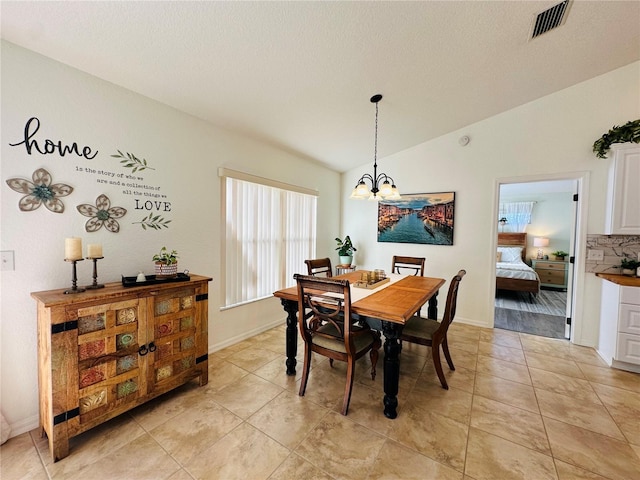 dining space featuring a chandelier, a textured ceiling, lofted ceiling, and light tile patterned flooring