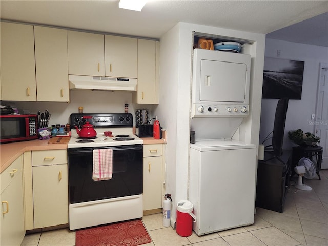 kitchen with stacked washing maching and dryer, white range with electric stovetop, cream cabinets, a textured ceiling, and light tile patterned flooring