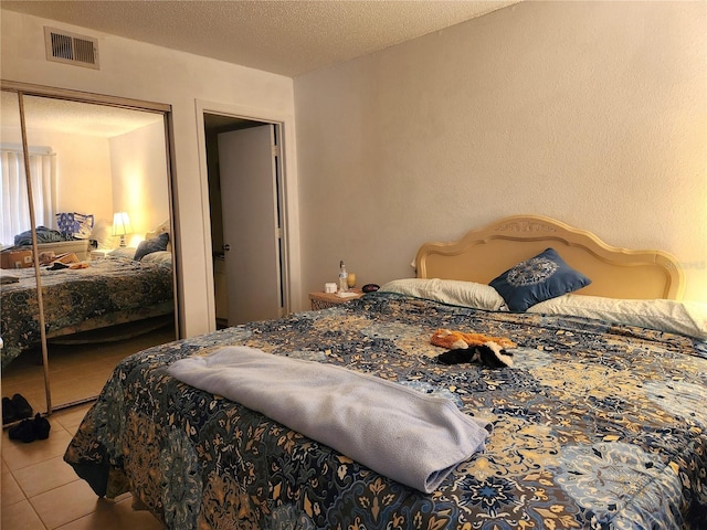 tiled bedroom with a closet and a textured ceiling