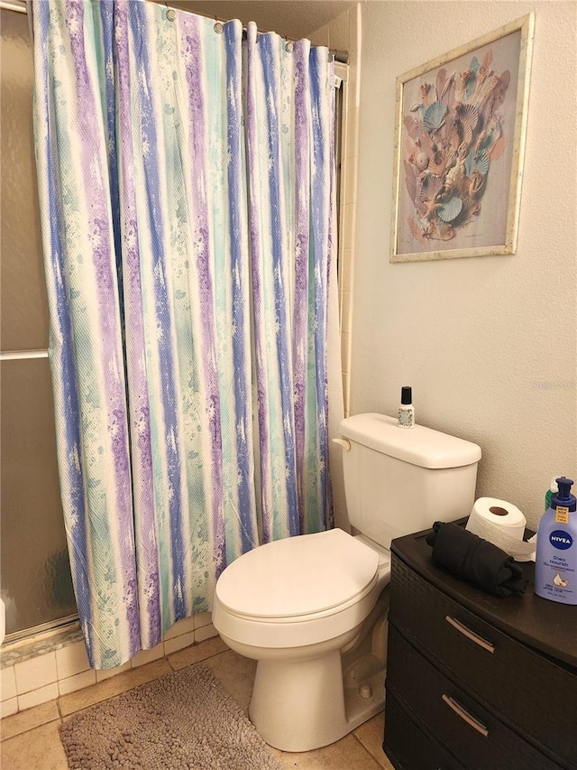 bathroom featuring tile patterned floors, curtained shower, and toilet