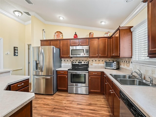 kitchen featuring tasteful backsplash, sink, ornamental molding, light hardwood / wood-style floors, and stainless steel appliances