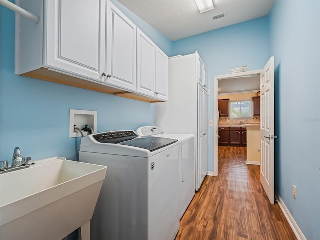 laundry area with cabinets, separate washer and dryer, sink, and dark hardwood / wood-style floors