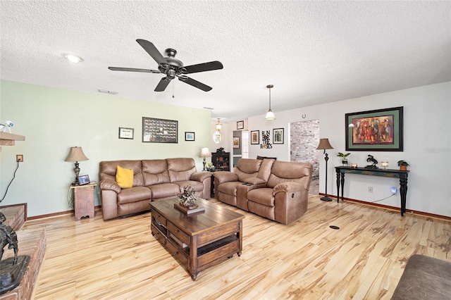 living room with a textured ceiling, light wood-type flooring, and ceiling fan